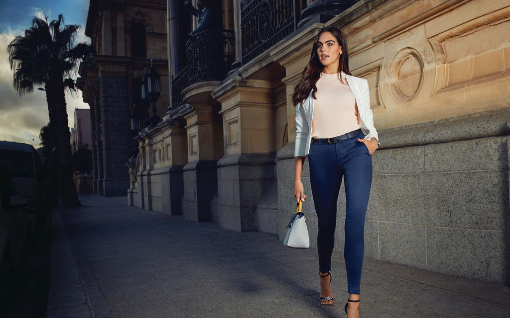 Image of a woman walking dressed in Go Colors Jeans and and a formal top.